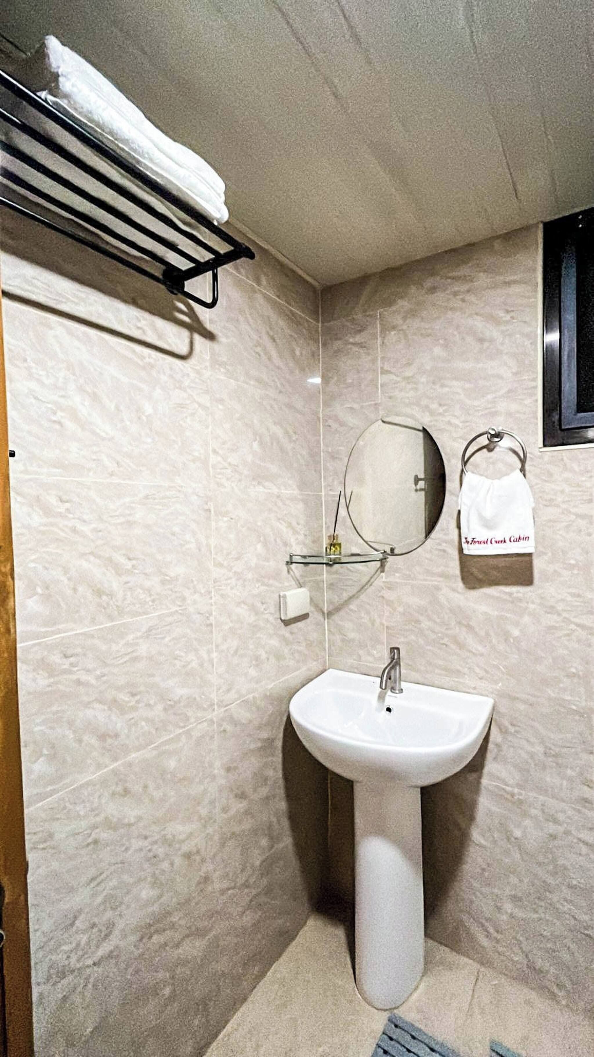 A bathroom with a pedestal sink, a towel rack, a mirror, and a towel hanging on the wall.