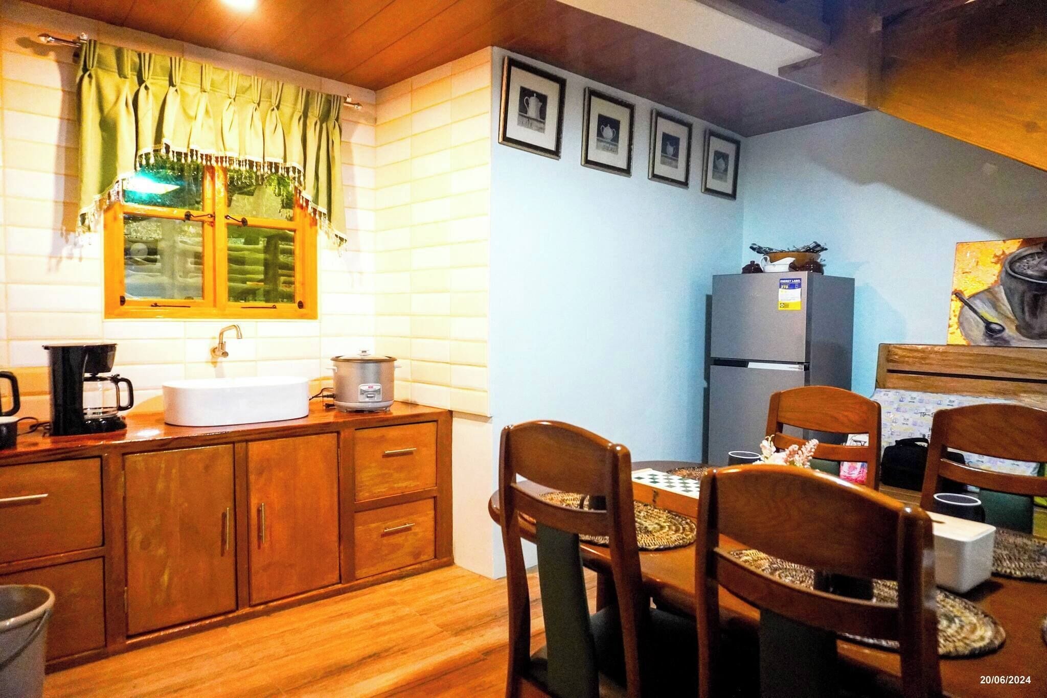 Una cocina compacta con armarios de madera, un lavamanos, una cafetera, un refrigerador y una mesa de comedor con sillas.
