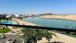 A coastal resort with a swimming pool, beach, and clear blue waters.