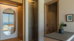 Casa de banho moderna com chuveiro de vidro, espelho redondo e vista para uma varanda.