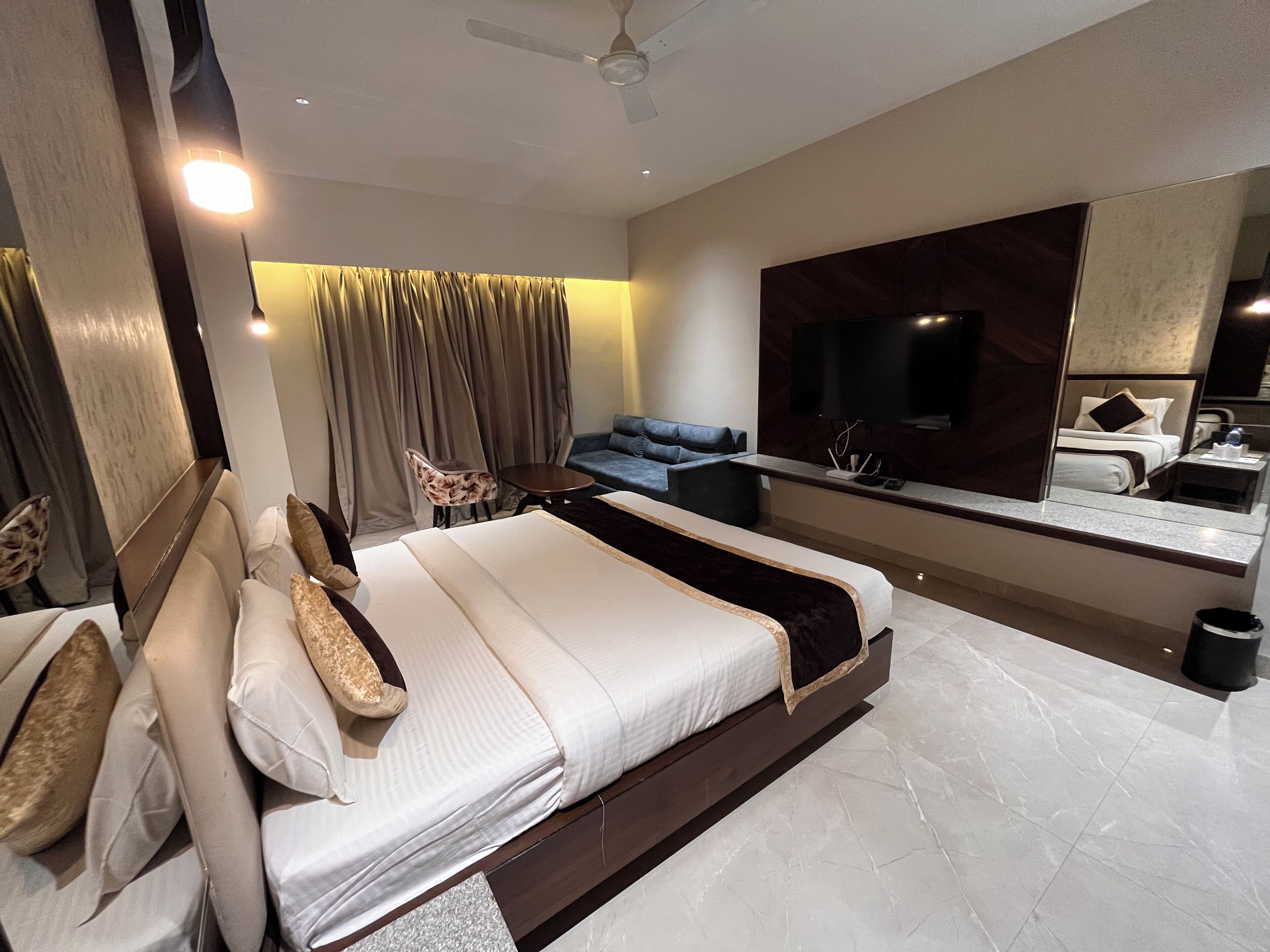 A modern hotel room with a large bed, a seating area, a TV, and a bathroom.