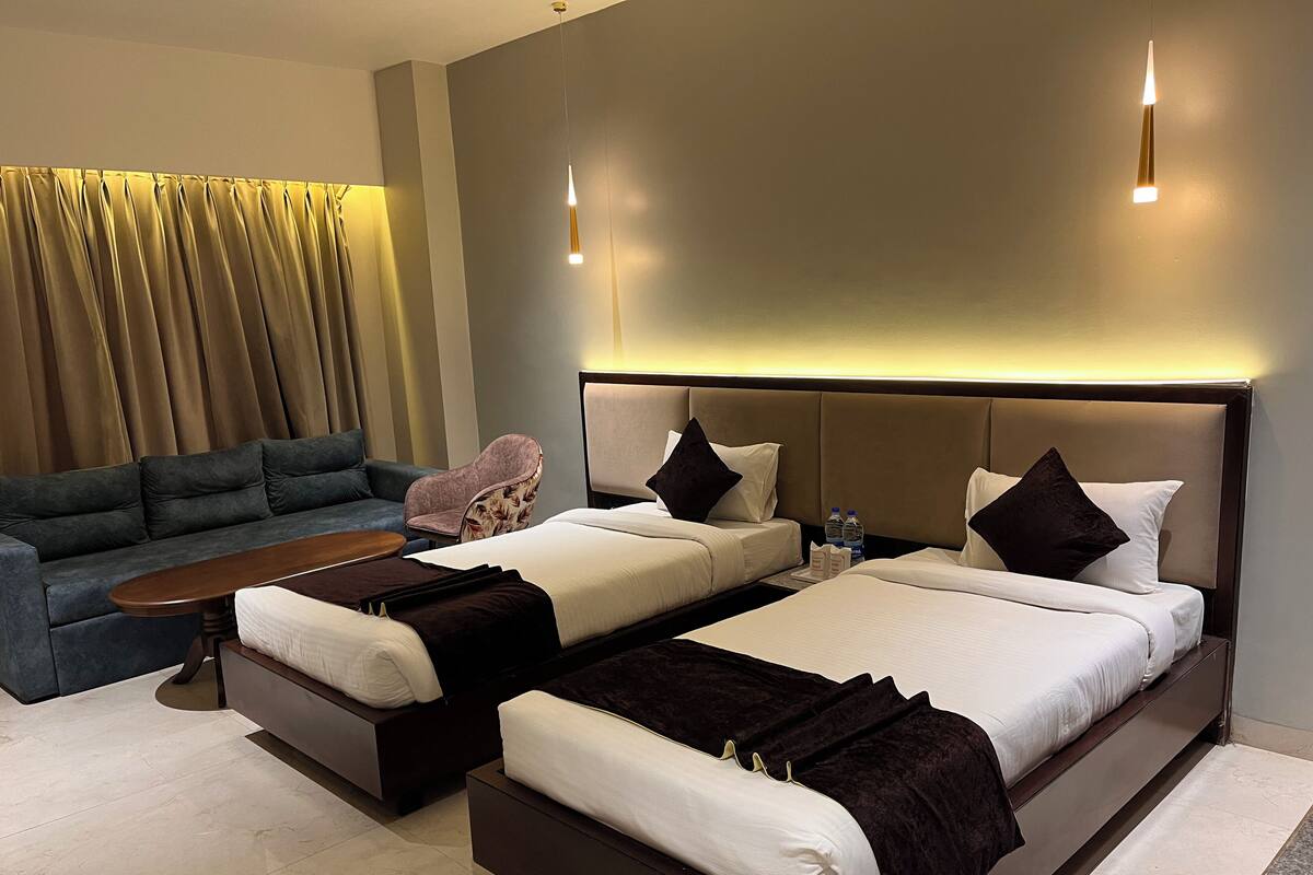 A hotel room with two beds, a sofa, a chair, and a small table.