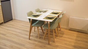 A dining area with a table set for four, green chairs, and a white tablecloth.