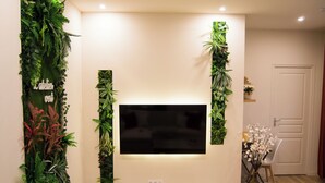 A living room with a flat-screen TV mounted on the wall, surrounded by vertical green plant installations.