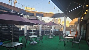 An outdoor patio with tables and chairs, covered by umbrellas, and a green carpet. - JINGOM STAY HOTEL (Seoul)