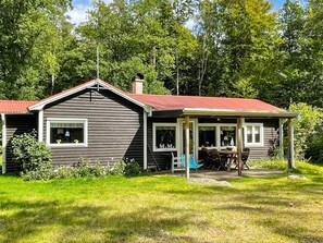 A cabin with a red roof, a porch with outdoor seating, and a window with the word "Move" on it. - 4 Person Holiday Home in Hastveda (Hästveda)