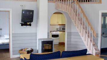 A compact living space with a loft area, a television mounted on the wall, a kitchenette, and a staircase.