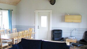 A room with a dining table, chairs, a mounted animal head, a door, and a small table with a lamp. - 4 Star Holiday Home in Ljung (Ljung)