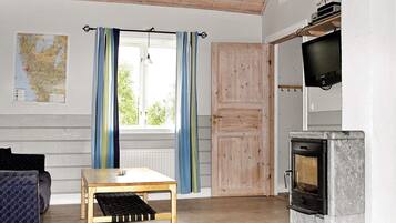 A room with a wooden table, a sofa, a map on the wall, a window with curtains, and a fireplace.