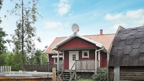 A red wooden house with a satellite dish, a wooden deck, and a wooden barrel. - 4 Star Holiday Home in Ljung (Ljung)