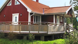 A red wooden house with a red-tiled roof, a porch, and a wooden deck. - 4 Star Holiday Home in Ljung (Ljung)