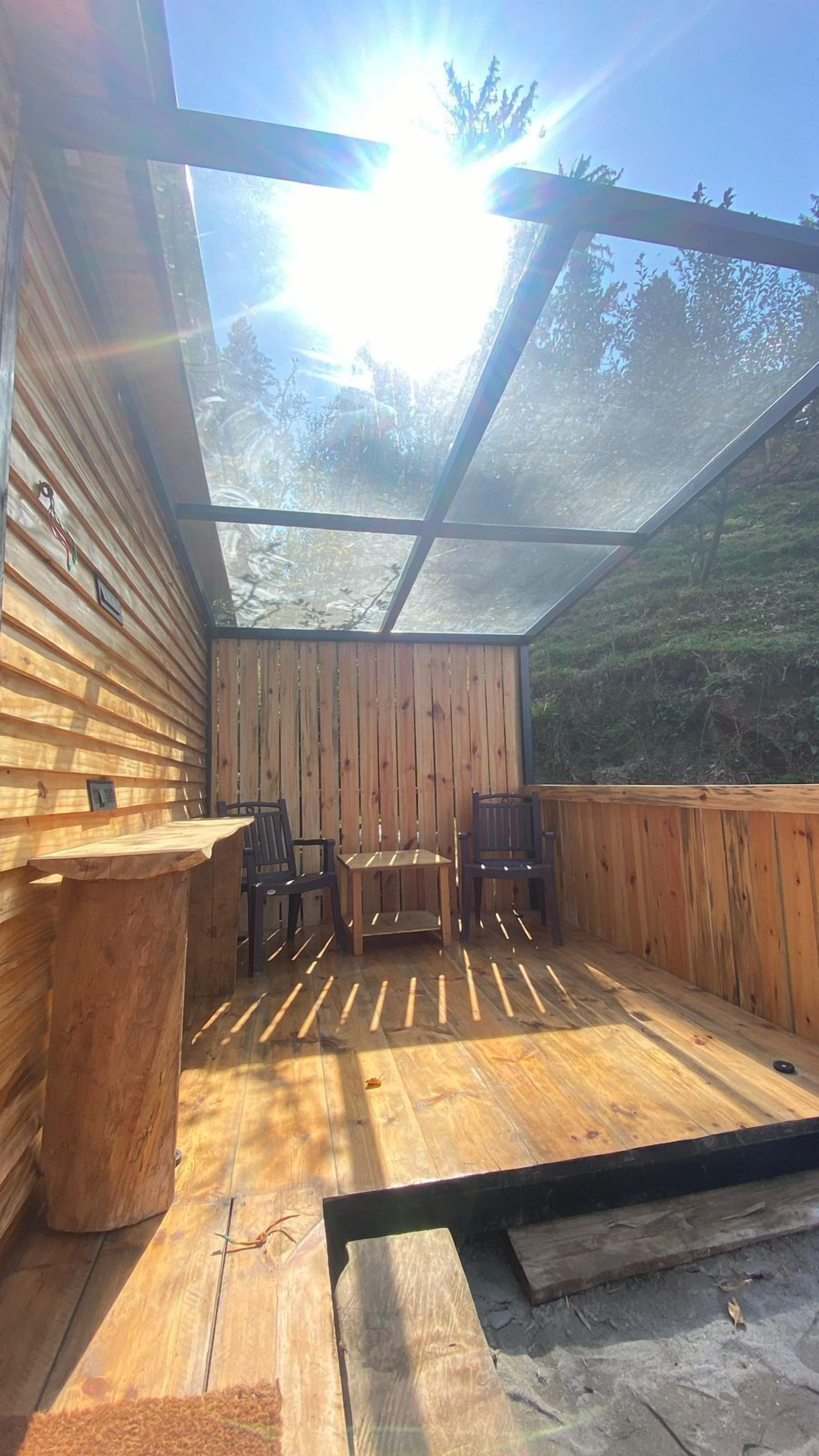 A covered outdoor seating area with wooden walls and a table and chairs.