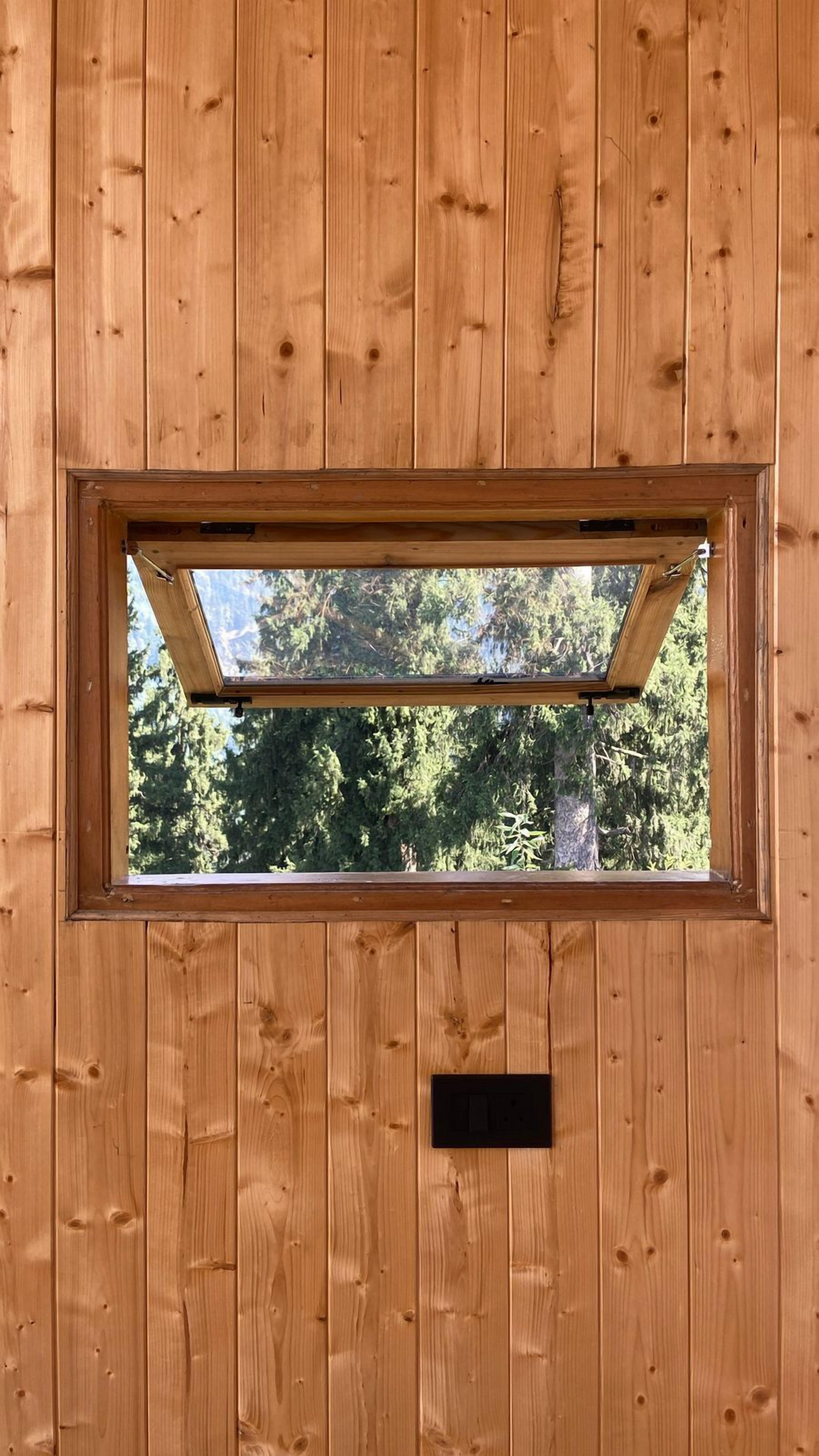 Un mur en bois avec une fenêtre rectangulaire et un interrupteur.