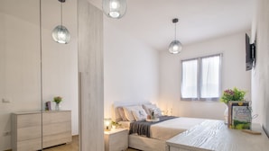 A modern bedroom with a bed, bedside tables, a mirror, and a window. - Posidonia by Interhome (Valledoria)