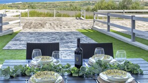 A dining table set outdoors with a view of the sea and hills. - Posidonia by Interhome (Valledoria)