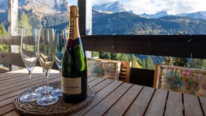 Une bouteille de champagne Moët & Chandon sur une table en bois, accompagnée de trois verres, le tout sur fond de paysage montagneux.