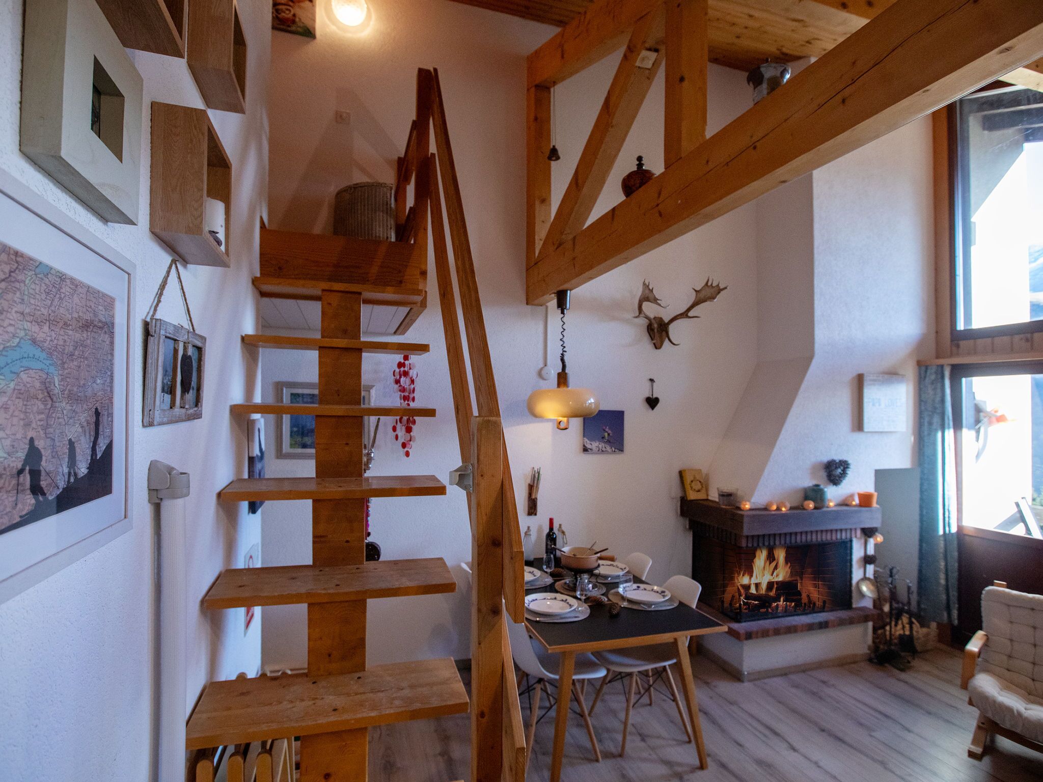 Ein rustikaler Innenraum mit einer Holztreppe, einer Essecke und einem Kamin.