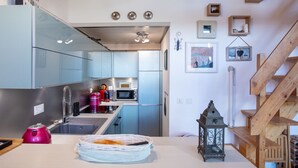 Une cuisine moderne dotée d’appareils électroménagers en acier inoxydable, de poutres en bois et d’un escalier.