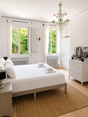 Een slaapkamer met een bed, een kaptafel, een nachtkastje en een raam met gordijnen.