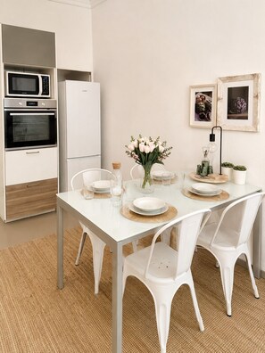 Een moderne keuken met witte kasten, een inbouwoven en een magnetron.