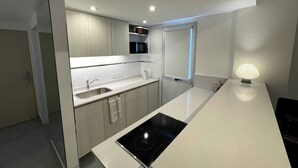 A modern kitchen with a central island, a built-in microwave, and a window with a view. - Fantastic Studio With Balcony Pool (Buenos Aires)