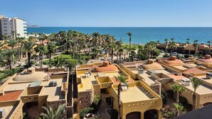 Een resort met meerdere gebouwen, palmbomen en uitzicht op zee.