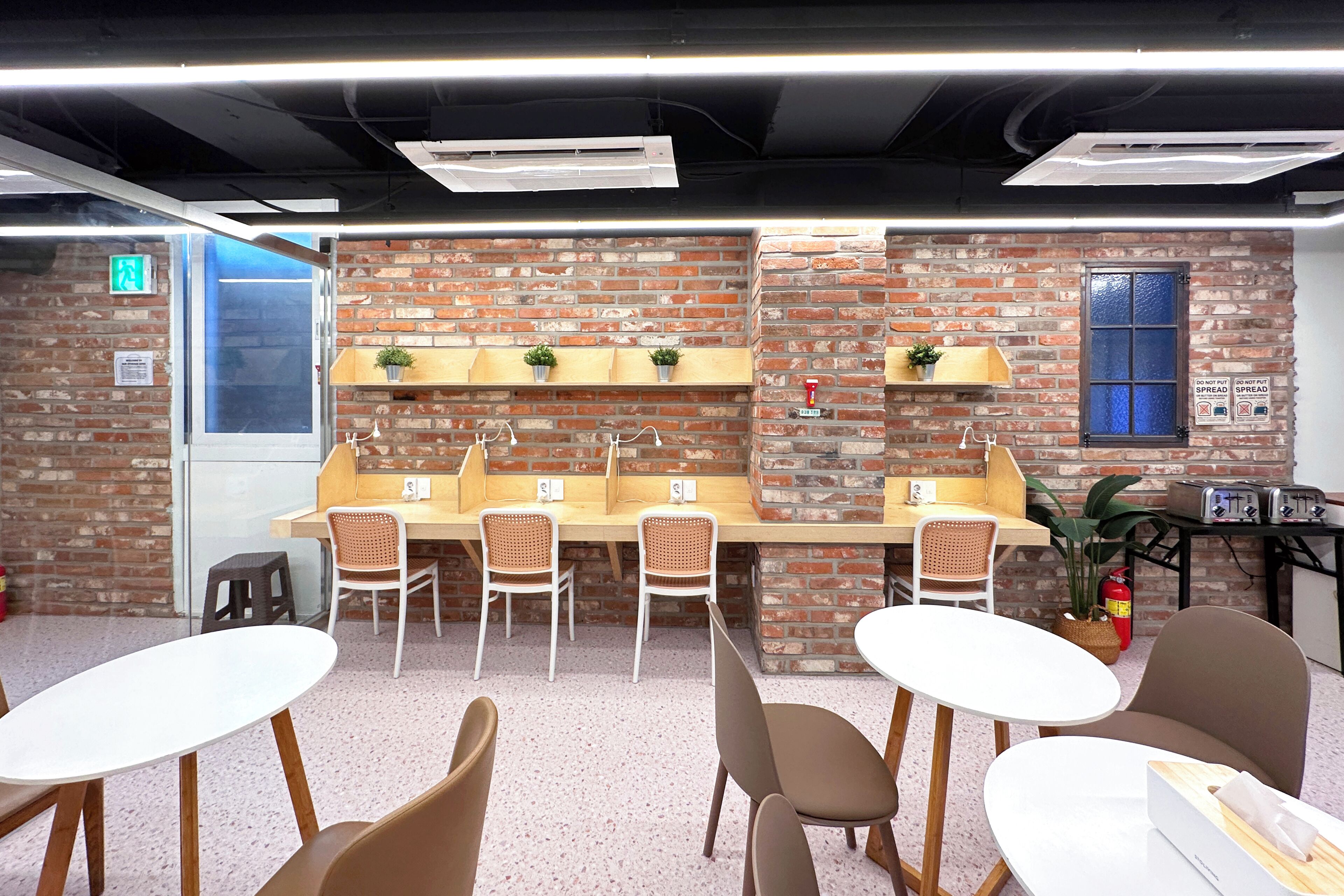 A modern indoor space with brick walls, a wooden counter with plants, and seating arrangements.