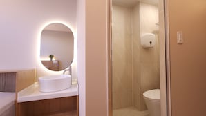 Une salle de bain moderne avec un miroir rond, un lavabo et des toilettes.