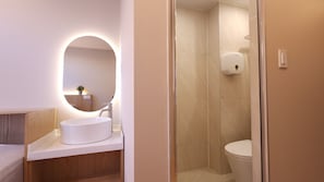 Een moderne badkamer met een ronde spiegel, een wastafel en een toilet.