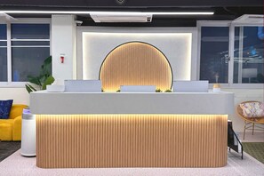 Een modern receptiebalie met een groot, rond houten paneel en een witte console.