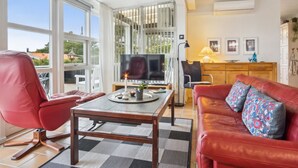 Un espacio habitable amplio con un sofá de cuero rojo, una mesa de centro de madera y un televisor.