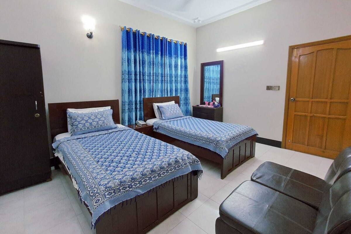 A room with two beds, a wooden wardrobe, a mirror, and a door.