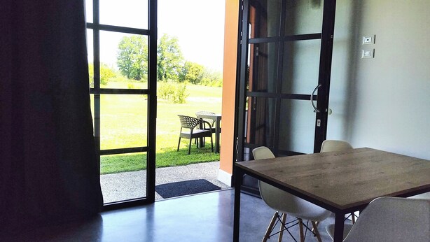 Une pièce dotée d’une grande porte-fenêtre coulissante donnant sur un espace extérieur aménagé avec une table et des chaises.
