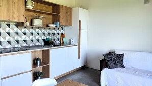 Une cuisine de taille réduite avec des meubles en bois, un plan de travail noir et un réfrigérateur blanc.