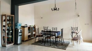 A dining area with a table and chairs, a chandelier, a water dispenser, and a hanging chair.