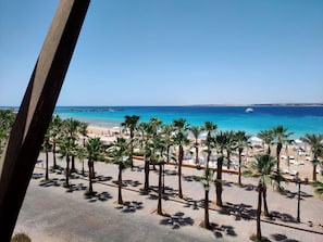 A beach with palm trees and a pier in the background. - Lux Garden house pool WiFi Hurghada (Hurghada)
