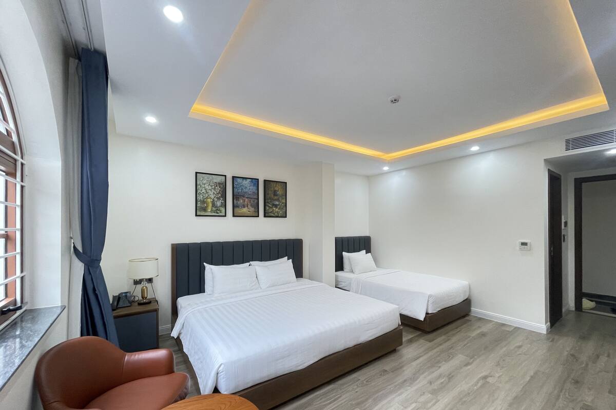 A hotel room with two beds, a desk, a chair, and a window with curtains.