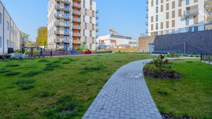 A modern urban residential area with a paved pathway, green spaces, and multi-story apartment buildings. - Cozy two room apartment near city center (Vilnius)