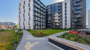 A modern apartment building with multiple balconies, a landscaped courtyard, and a paved pathway. - Cozy two room apartment near city center (Vilnius)