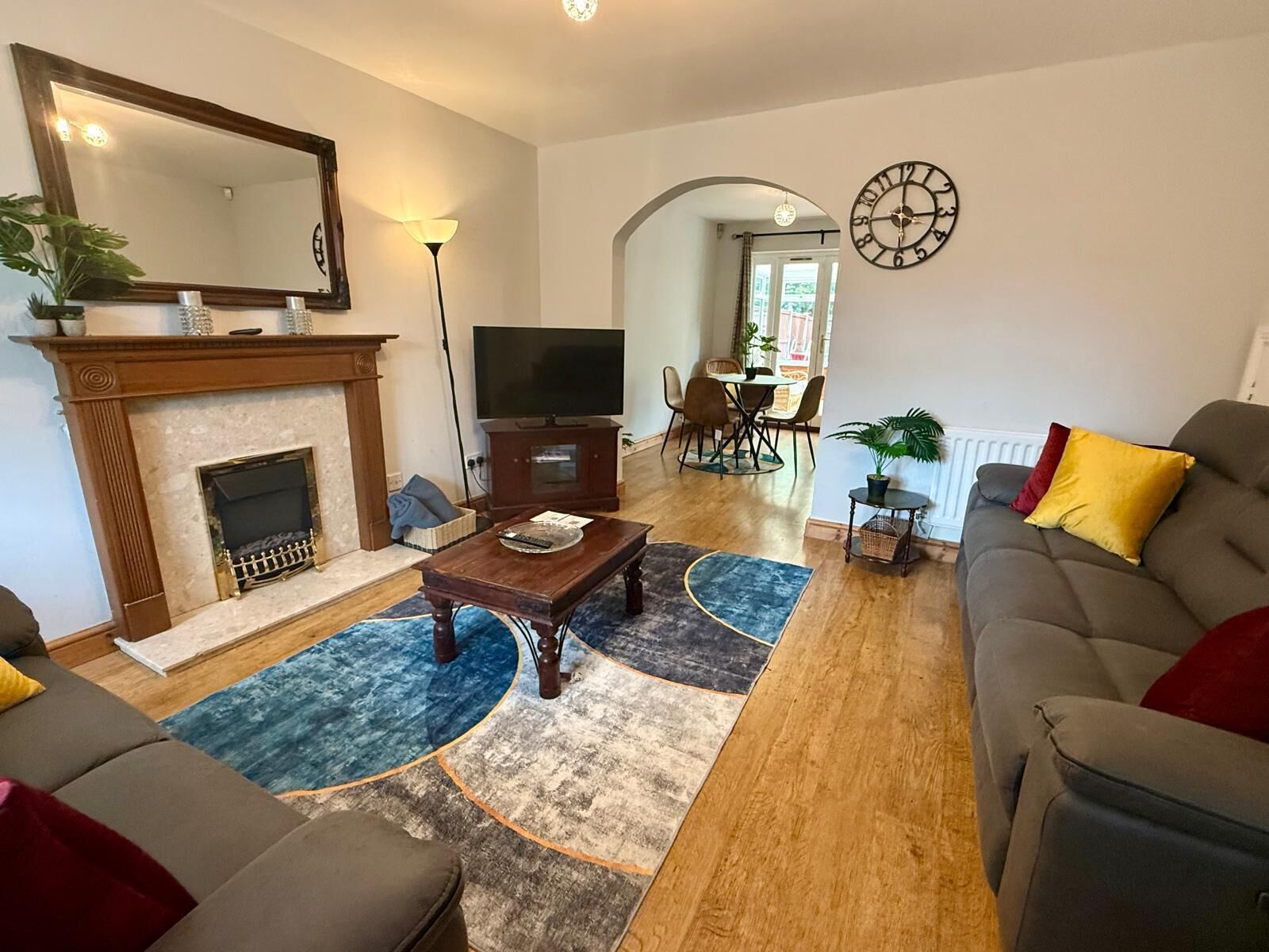 A living room with a fireplace, a television, a sofa, and a dining area with chairs.