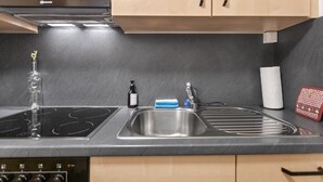 A kitchen with a black countertop, stainless steel sink, and a built-in stove. - Saas-Fee center - 2 bedrooms - balcony and patio (Saas-Fee)