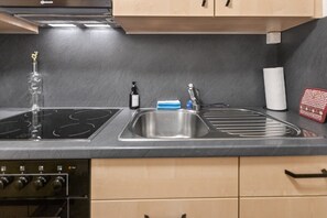 A kitchen with a black countertop, stainless steel sink, and a built-in stove. - Saas-Fee center - 2 bedrooms - balcony and patio (Saas-Fee)