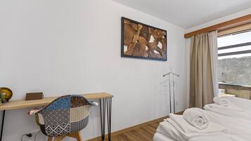 Ein Hotelzimmer mit einem Bett, einem kleinen Schreibtisch mit Stuhl, einem Kleiderständer und einem Fenster mit Vorhängen.
