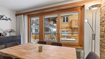 Un comedor con una mesa de madera, sillas y vistas a un edificio con balcones.