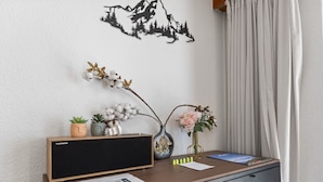 A desk with a Thomson speaker, two potted plants, a vase with flowers, and a decorative wall piece. - Saas-Fee center - 2 bedrooms - balcony and patio (Saas-Fee)