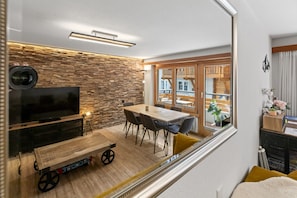 Ein modernes Wohnzimmer mit einer Steinsäule, einem Holzesstisch und einem Fernseher.