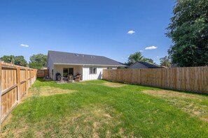Ein Garten mit einem Haus, einem Holzzaun und einem Rasen.