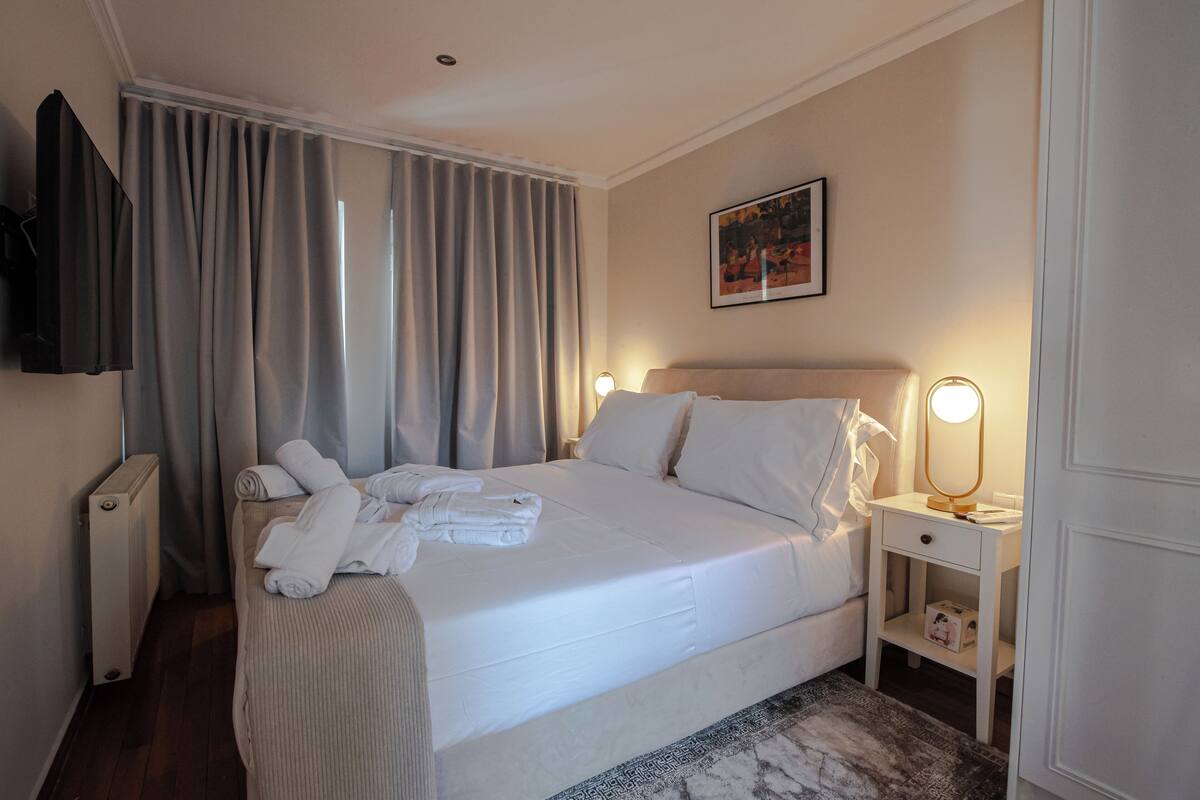 Un lit bien fait, avec du linge de lit blanc, une table de chevet avec une lampe et un radiateur.