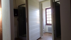 A hallway with a glass shower enclosure, a radiator, and a window with a view. - Beautiful, large family home (Nant)