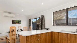 Una cocina moderna con armarios de madera, encimera blanca y un amplio ventanal con cortinas.